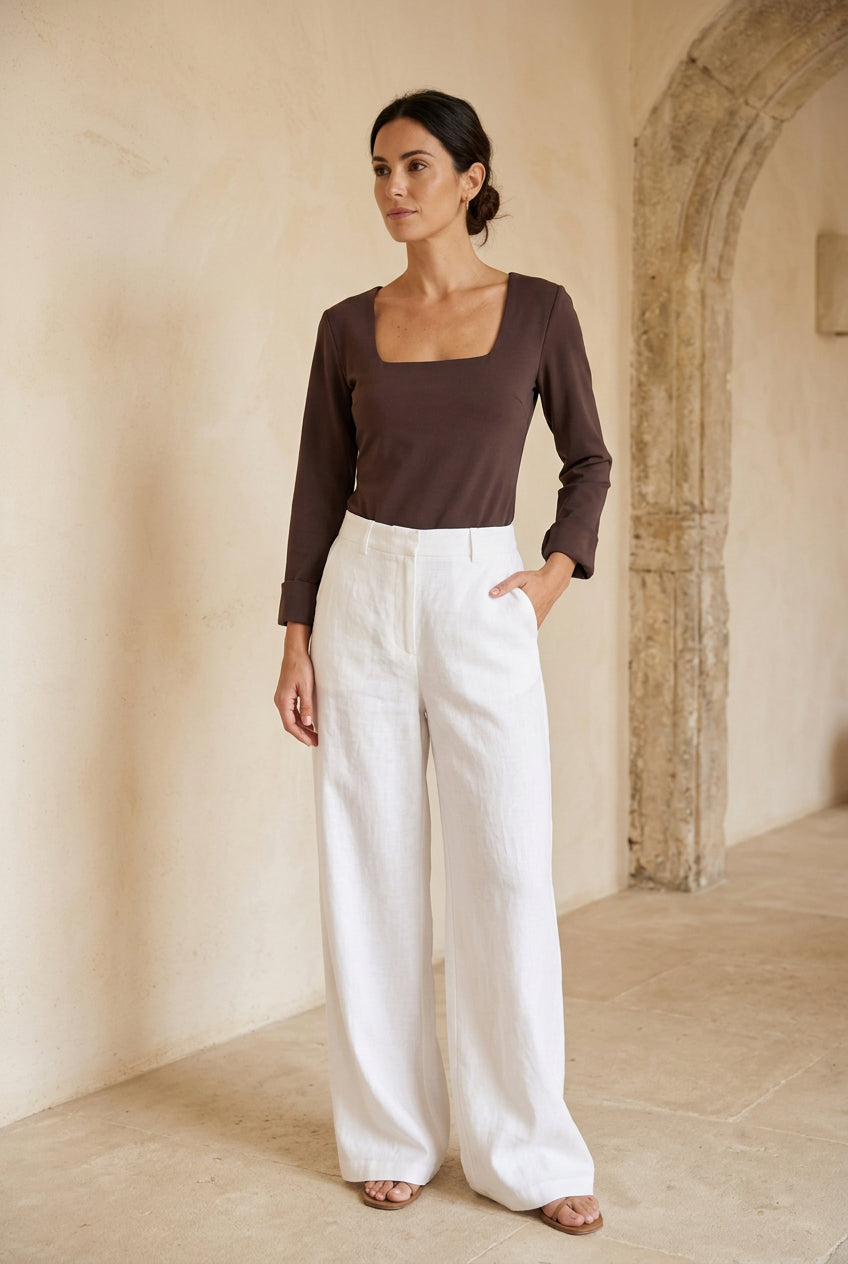 Six women's long-sleeve bodysuits in different colors (beige, navy, charcoal, burgundy, cream, and brown) are displayed on a black clothing rack against a plain white wall.