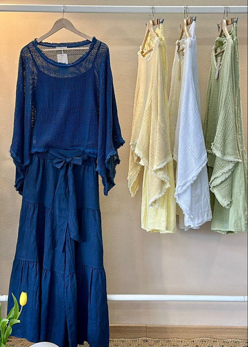 Blue set hanging on a rack with other colorful linen sets in a room.