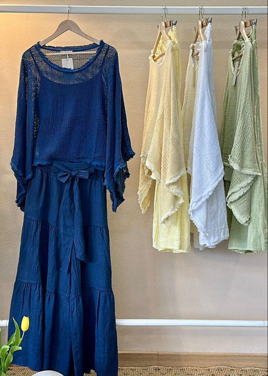Blue set hanging on a rack with other colorful linen sets in a room.