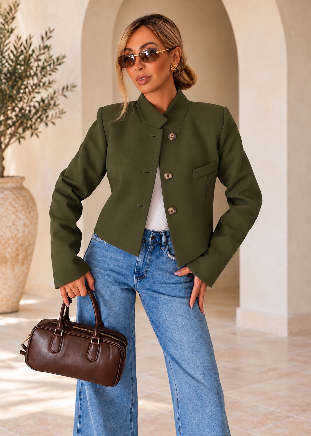 Olive green cropped blazer worn open, with round brown and beige plastic buttons on the inner panel and buttonholes on the outer panel