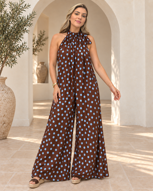 Modelo con La Dolce Vita Jumpsuit marrón de lunares azules, escote halter y pantalón palazzo