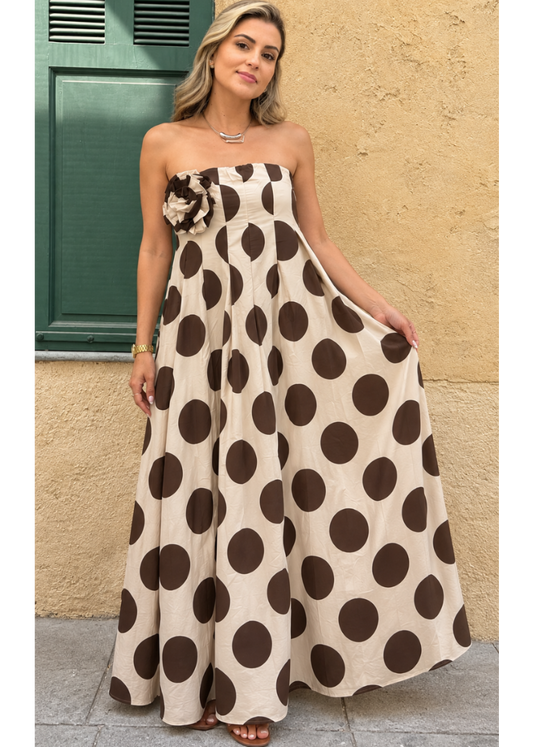 Modelo con vestido largo beige de lunares marrones grandes y flor de tela