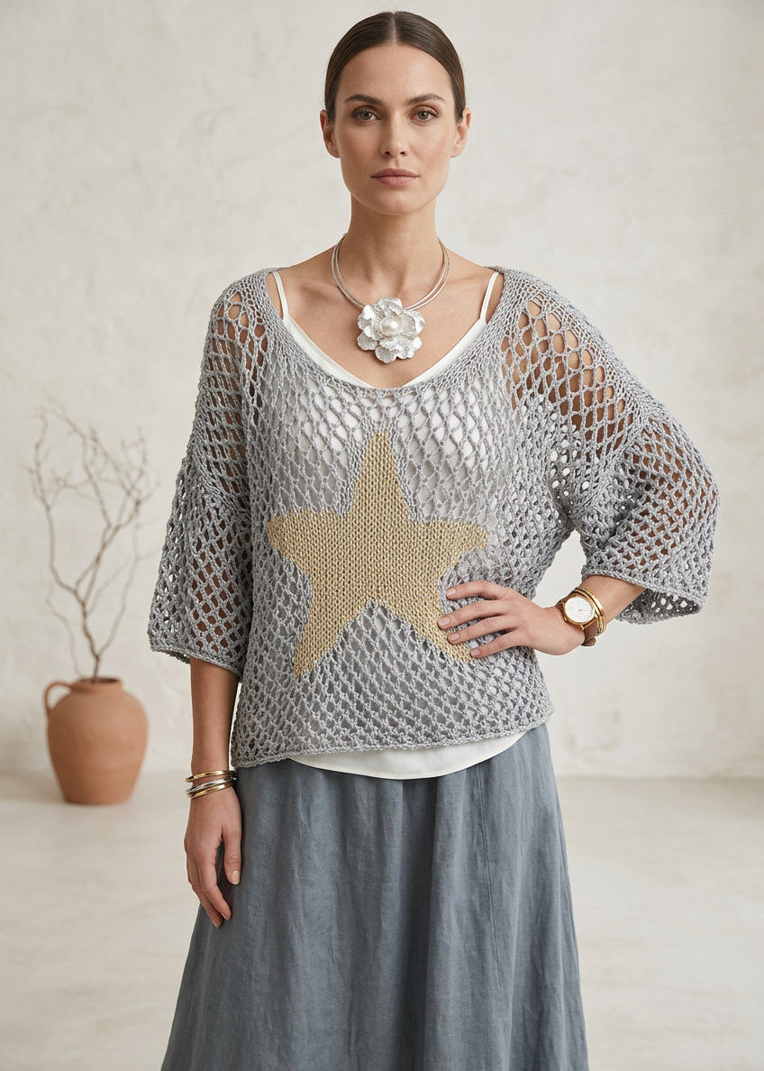 Person wearing a gray knit cardigan with a star design outdoors. crochet 