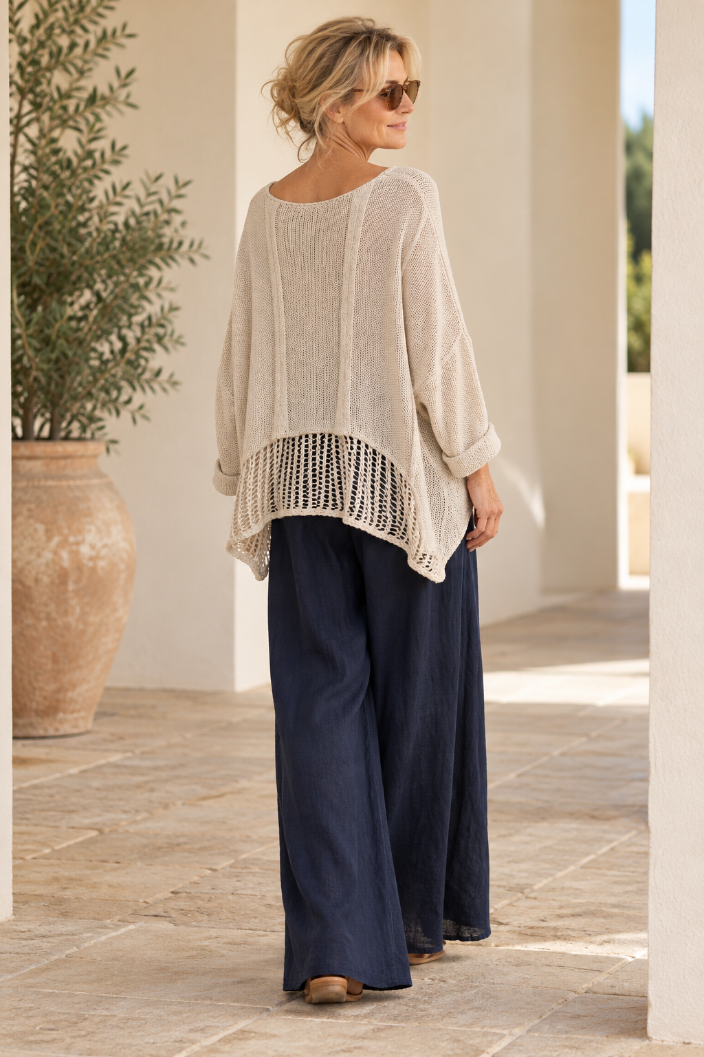 Back view of the beige Italian cotton poncho sweater showing the open stitch mesh hem